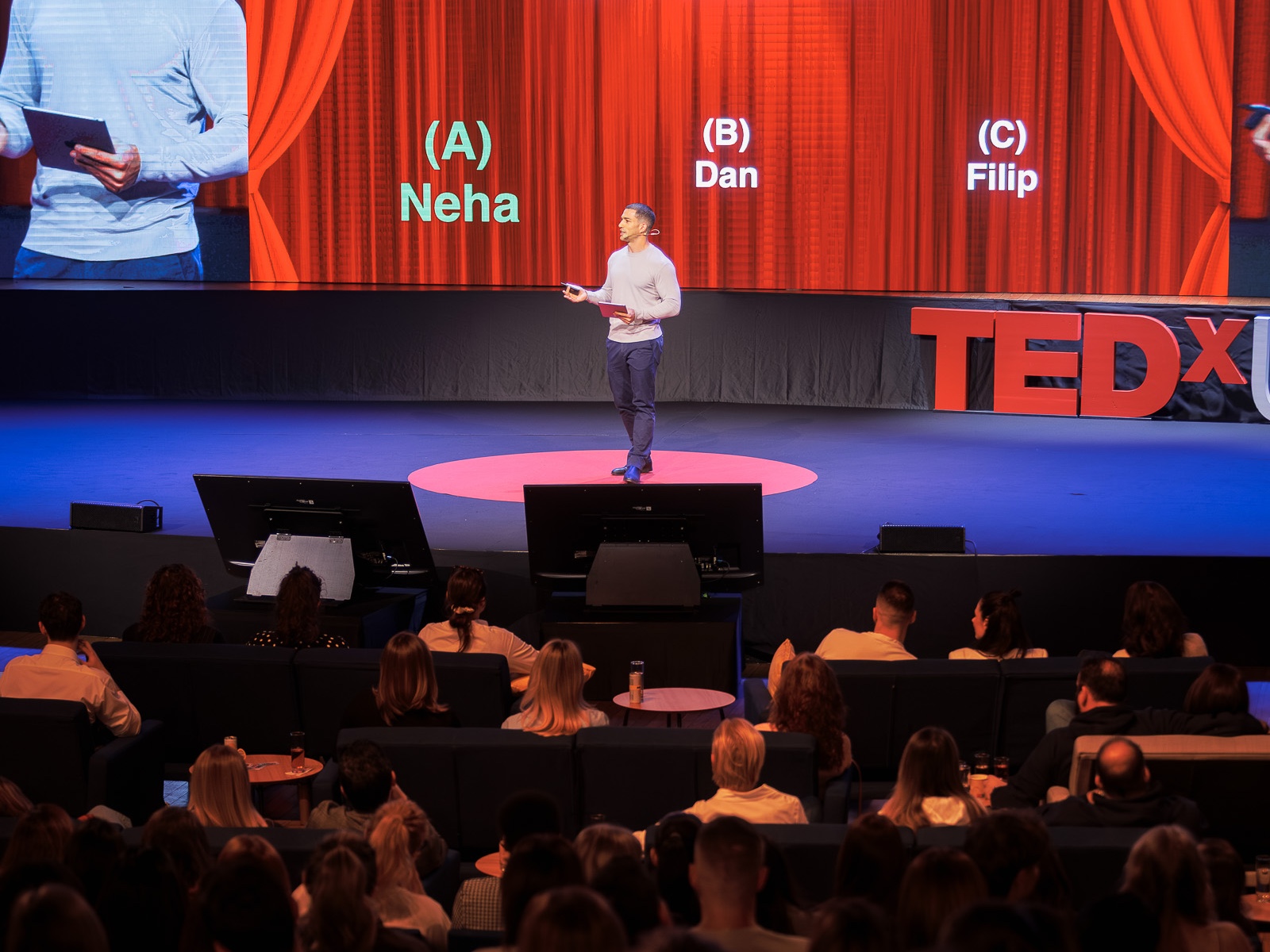 Amit Grinvald presenting on the TEDxUNYP stage in front of an audience